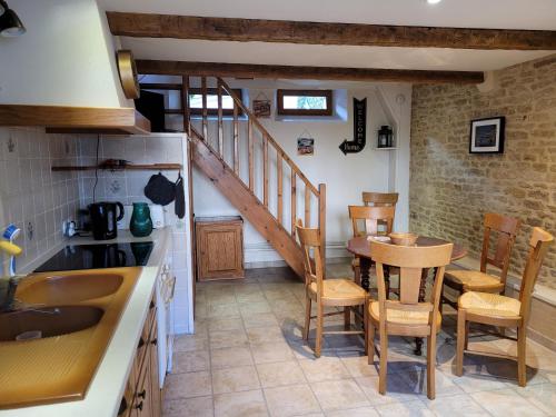 une cuisine et une salle à manger avec une table et des chaises dans l'établissement Maison de pêcheur charmante et atypique en pierre, 1 min de marche de la mer, à Saint-Aubin-sur-Mer