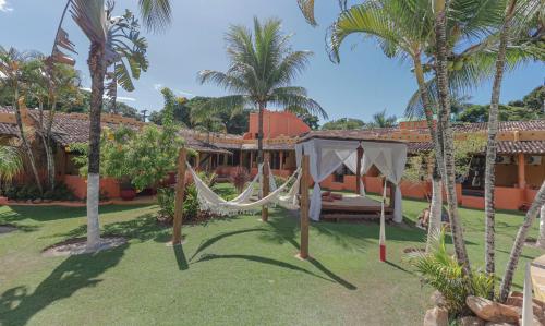a resort with a hammock in a yard with palm trees at Estação Santa Fé Hotel e Pousada in Arraial d'Ajuda