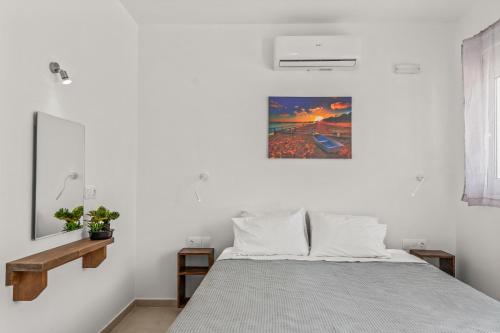 a white bedroom with a bed and a painting on the wall at summer paradise stegna rhodes in Archangelos