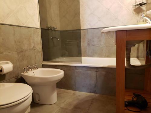 een badkamer met een toilet, een wastafel en een bad bij Cálido departamento 2 dormitorios - Céntrico in San Martín de los Andes