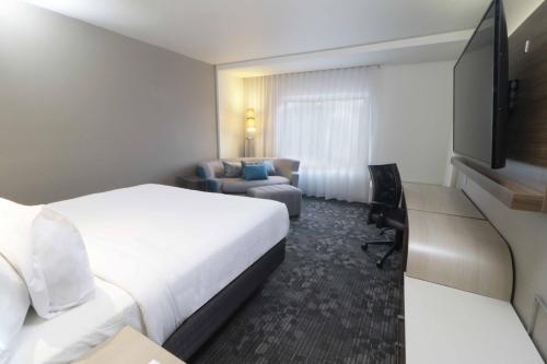une chambre d'hôtel avec un lit et un canapé dans l'établissement Courtyard Monterrey Airport, à Monterrey