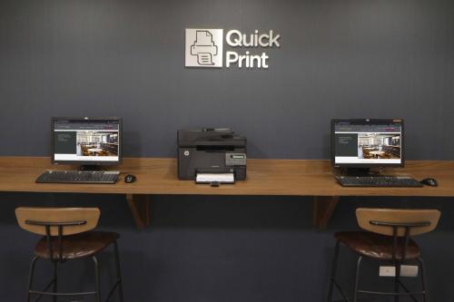 a counter with three computers and a printer on it at Courtyard Monterrey Airport in Monterrey