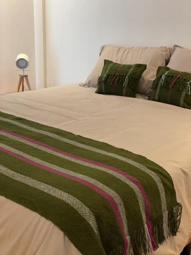 a bed with a green and pink blanket on it at Departamento Rosas in Ushuaia