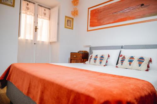 a bedroom with a bed with an orange blanket on it at Casetta Zia Maria in Carloforte
