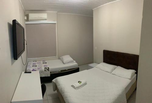 a small room with two beds and a tv at HOTEL LIFE IJUI in Ijuí