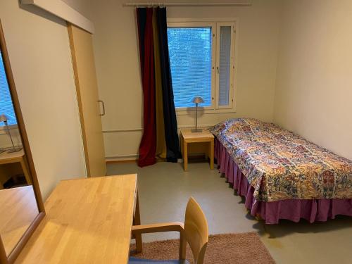 a bedroom with a bed and a table and a window at Grand Hostel Imatra in Imatra