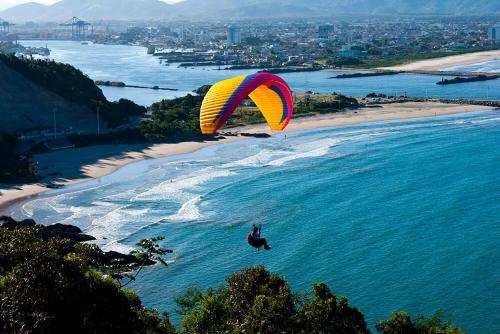 a person in the air with a parachute over the ocean at Adry Hotel Inn Itajaí Navegantes in Itajaí