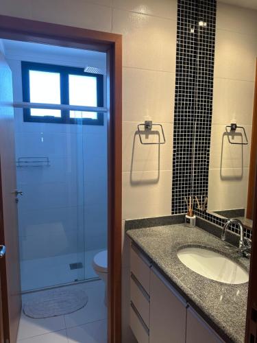 a bathroom with a sink and a toilet and a glass door at A Melhor vista de água de Lindóia in Águas de Lindóia