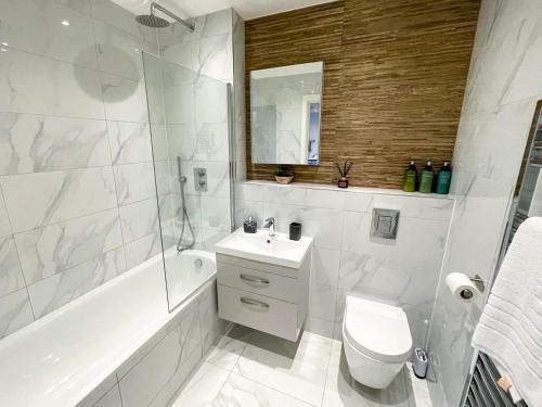 La salle de bains blanche est pourvue d'une baignoire, de toilettes et d'un lavabo. dans l'établissement Brand New Apartment in the Heart of Chelmsford, à Chelmsford