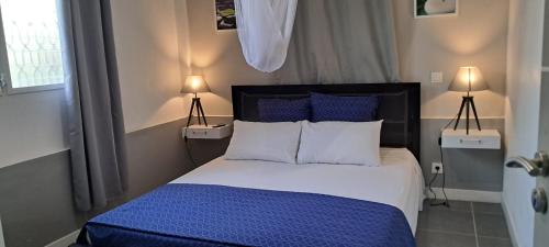 1 dormitorio con 1 cama con sábanas y almohadas azules en Beau F2 classé, vue mer, spa, jardin, bateau, en Le Robert