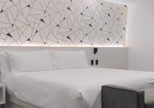 1 dormitorio con cama blanca y pared en The Andy Hotel en Querétaro