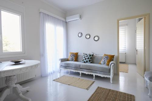 a white living room with a couch and a mirror at Mosaic Cosy House in Chios