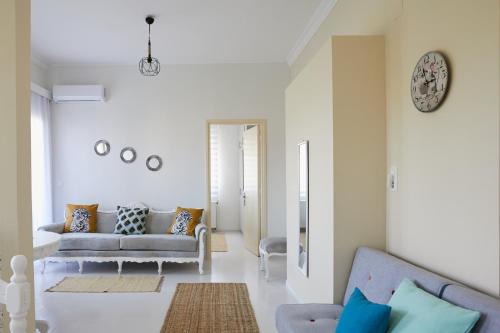 a living room with a couch and a clock on the wall at Mosaic Cosy House in Chios