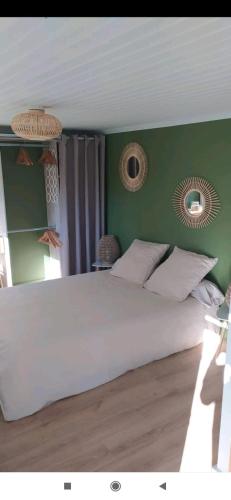 a bedroom with a large white bed with green walls at Studio indépendant au calme in Angers