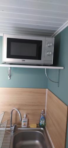 eine Mikrowelle auf einem Regal über einer Küchenspüle in der Unterkunft Studio indépendant au calme in Angers