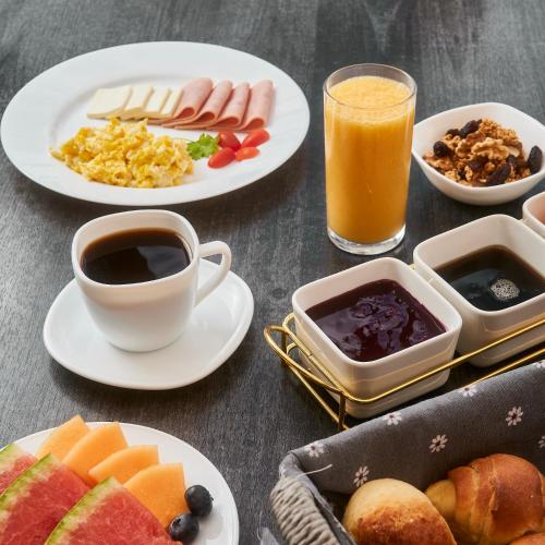 a table topped with plates of breakfast foods and drinks at Hotel & Suites en Cuenca, Venue Batán in Cuenca