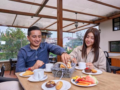 a man and woman sitting at a table with food at Hotel & Suites en Cuenca, Venue Batán in Cuenca
