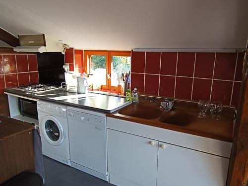 a kitchen with two sinks and a washing machine at Gite du pic vert in Rivèrenert