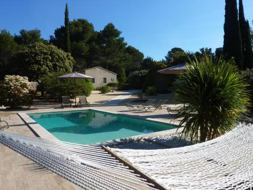 a swimming pool with a hammock in a yard at Les Mazets du Luberon in Puget