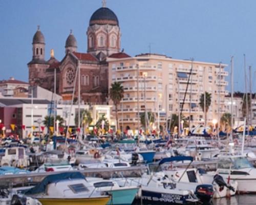 un groupe de bateaux amarrés dans un port avec un bâtiment dans l'établissement Floramarine, à Saint-Raphaël