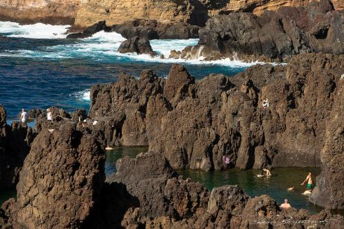 a group of people swimming in the ocean near rocks at Porto Moniz Villa in Porto Moniz