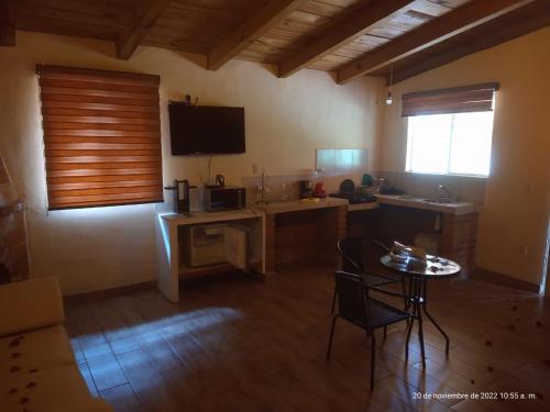 a room with a kitchen with a table and a television at Rincón del Bosque in Mazamitla