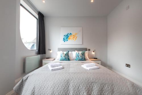 een witte slaapkamer met een groot bed met 2 kussens bij Kingsbridge House Apartment Four - Free Parking - Heathrow - Thorpe Park in Staines