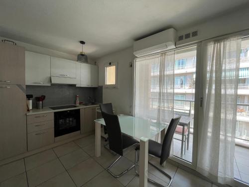 une cuisine avec une table et des chaises en verre ainsi qu'une fenêtre dans l'établissement Le Cheret, à Nice