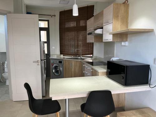 eine Küche mit einer Theke mit 2 Stühlen und einer Mikrowelle in der Unterkunft John House studio No 5 in Flic-en-Flac