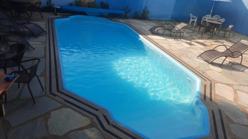 una gran piscina con sillas y una mesa en Pousada Estrela Guia en Pirenópolis