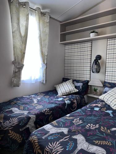 a bedroom with two beds and a window at Porthcurno 4, Silverbow Country Park in Perranzabuloe