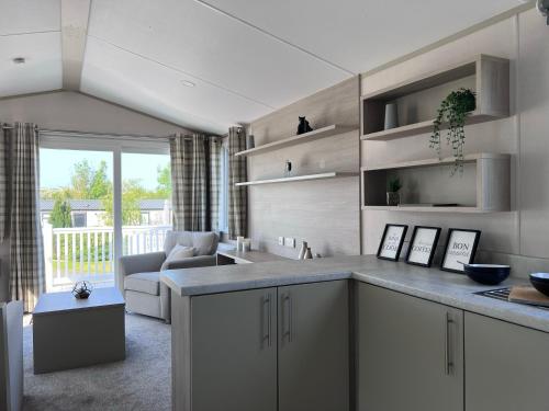 a kitchen with white cabinets and a living room at Porthcurno 4, Silverbow Country Park in Perranzabuloe