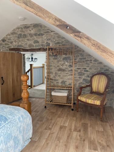 a bedroom with a stone wall and a bed and a chair at Pippin Lodge in Llanwrda