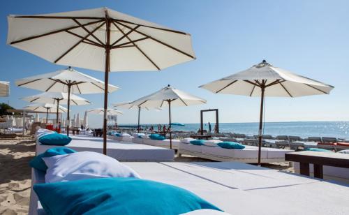a beach with white umbrellas and chairs and the ocean at Hotel Otrada in Odesa