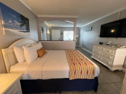 una camera con un letto e un comò con una televisione di Pelican Pointe Hotel a Clearwater Beach