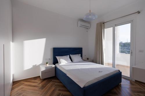 a bedroom with a blue bed and a large window at CAPTAIN'S RESIDENCE in Ksamil