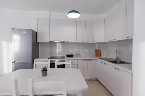 a kitchen with white cabinets and a white table at CAPTAIN'S RESIDENCE in Ksamil