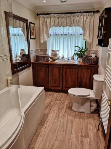 a bathroom with a tub and a toilet and a sink at Maywalk House B&B in Eyam