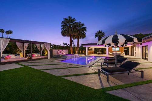 a house with a pool with chairs and an umbrella at THE BANK Mid-Century Luxury Resort Palm Springs in Palm Springs