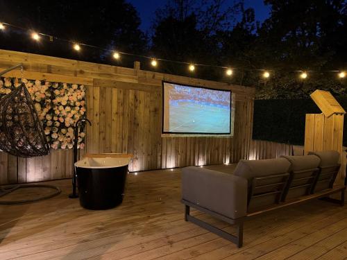 un patio con sofá y TV en una terraza de madera en Calon, en Tenby