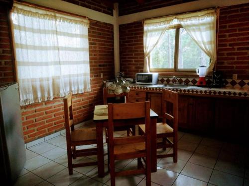 a kitchen with a table and chairs and two windows at Rincón del Bosque in Mazamitla