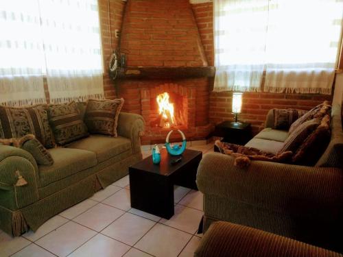 a living room with two couches and a fireplace at Rincón del Bosque in Mazamitla