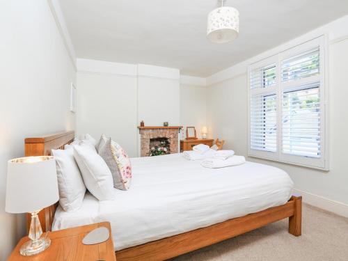 Dormitorio blanco con cama blanca y chimenea en Crew House en Dartmouth