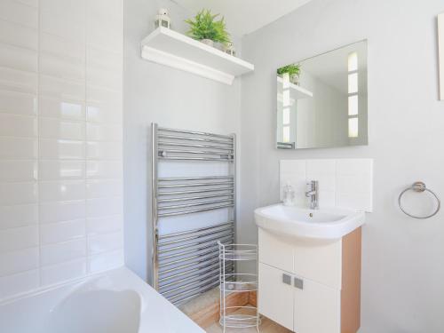 Baño blanco con lavabo y espejo en Crew House en Dartmouth