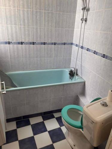 a bathroom with a blue tub and a toilet at Centre ville de Nevers. in Nevers