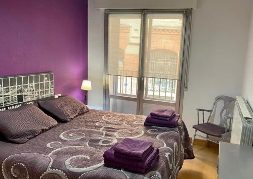 a bedroom with a bed with purple walls and a window at Apartamento Berria in Pamplona