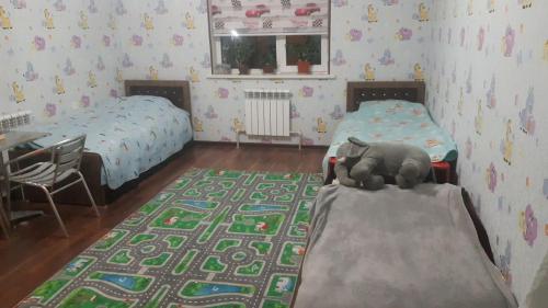 a bedroom with two beds and a stuffed elephant on the floor at Квартира для 5 человек в Нукусе in Nukus