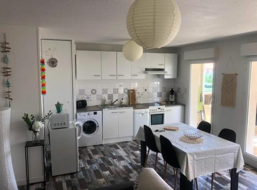 een keuken met een tafel en een eetkamer bij T2, bord de plage et piscine in Biscarrosse