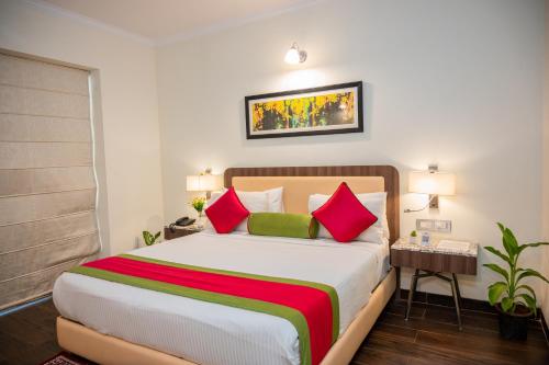 a bedroom with a large bed with red and green pillows at La Oasis by Meraden ,Goa in Anjuna