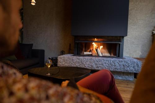 a woman sitting in front of a fireplace at Le 11 des Bouchaux, Gîte d'exception in La Bresse